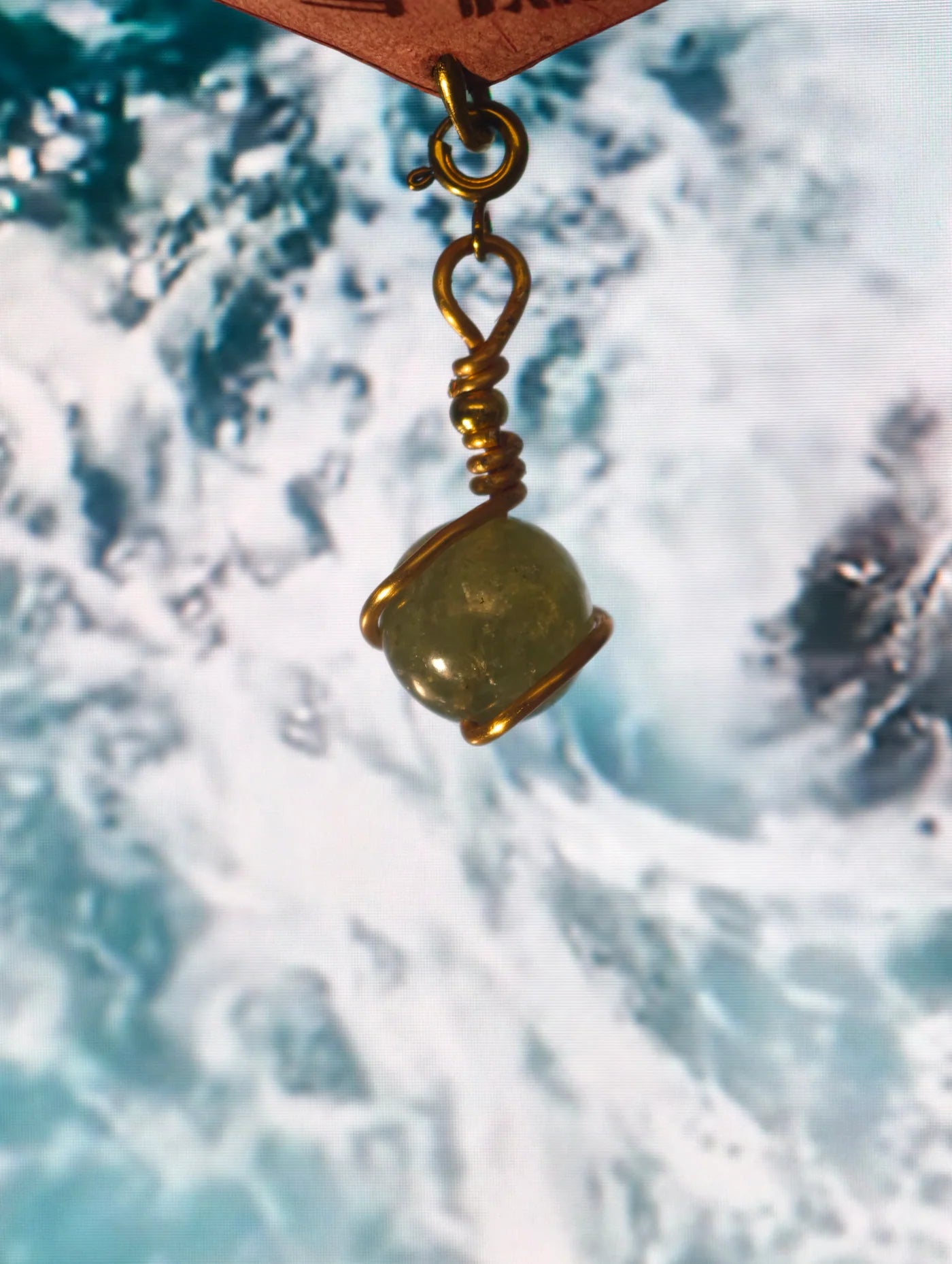 Close view of a wire-wrapped green natural-stone charm