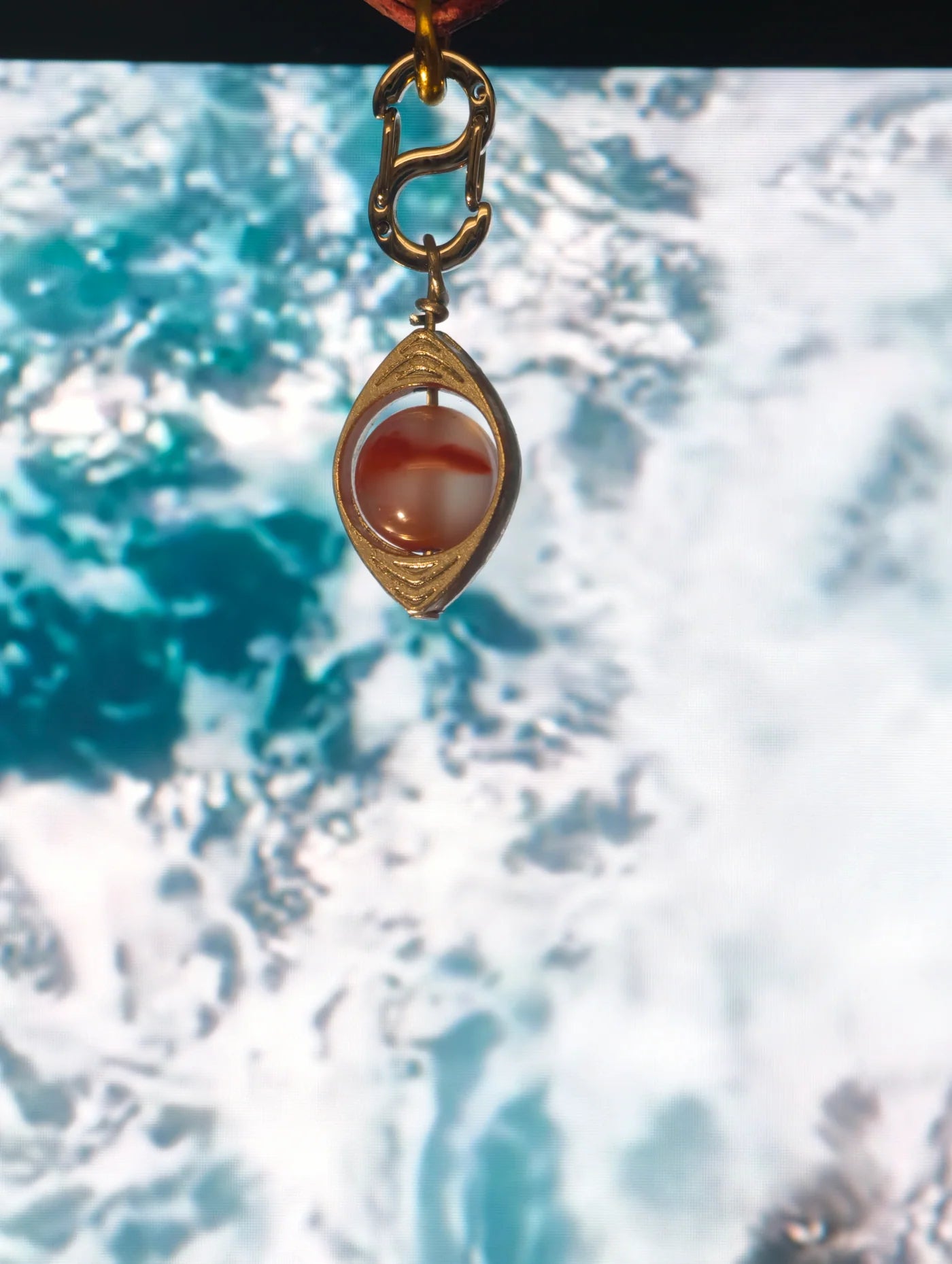 Warm red banded natural-stone charm in a gold-toned setting